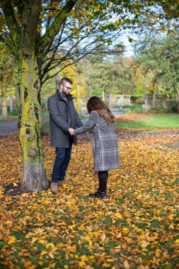 Güz ormanlarında el ele tutuşan siyah saçlı beyaz Avrupalı kadın ve erkek.