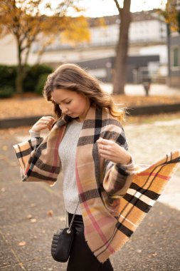 Sonbaharda yürüyen kahverengi saçlı, beyaz Avrupalı genç kadına bakıyorum.