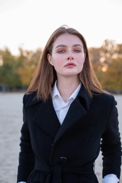 ビーチで秋に暗いコートの長いストレートの髪の白いヨーロッパの女性の肖像画 — ストック写真
