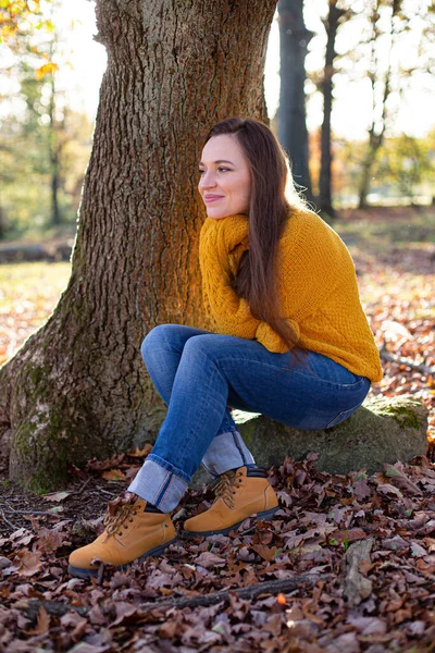 在阳光明媚的秋天森林里 穿着黄色毛衣的白衣年轻的欧洲姑娘微笑着 — 图库照片