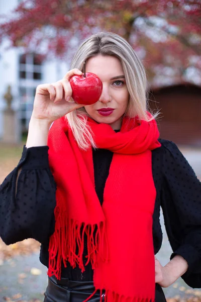 穿着红领巾 头戴金黄色头发的欧洲白人年轻女子手持红苹果的画像 — 图库照片