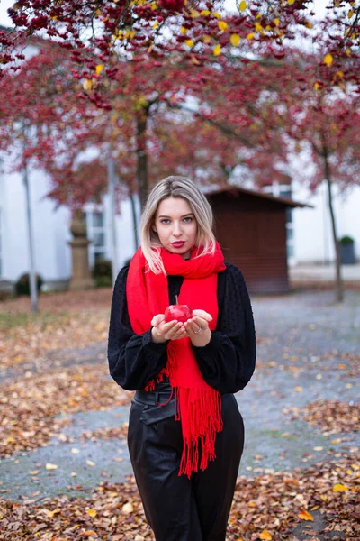 身穿红围巾金发碧眼的欧洲白人年轻女子拿着一个红苹果 — 图库照片