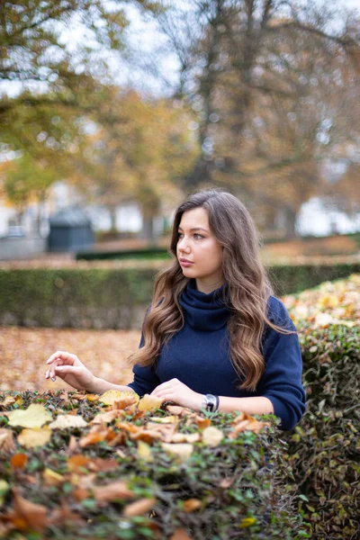 Młoda Europejka Ciemnoniebieskim Swetrze Długimi Kręconymi Włosami Jesiennym Parku Stojącym — Zdjęcie stockowe