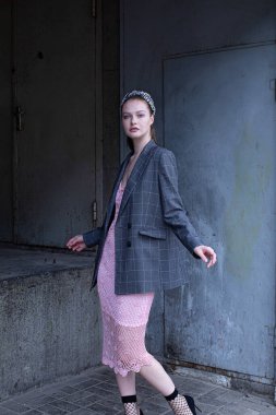 Beyaz, sarışın, at kuyruklu, gri ceketli, endüstriyel alanda mavi gözlü genç bir kadın.