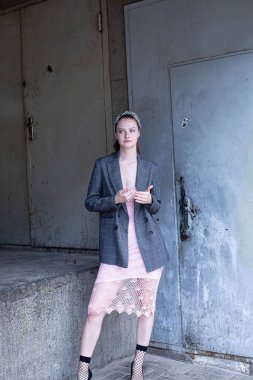 Beyaz, sarışın, at kuyruklu, gri ceketli, endüstriyel alanda mavi gözlü genç bir kadın.