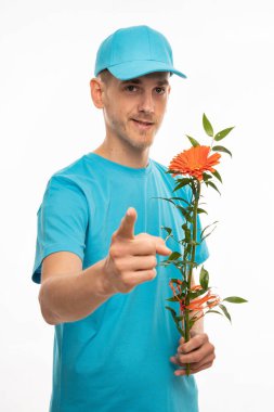 Genç yakışıklı, uzun boylu, zayıf, kahverengi saçlı, turuncu çiçekli beyaz adam beyaz arka planda izole edilmiş mavi gömlekli sana bakıyor.