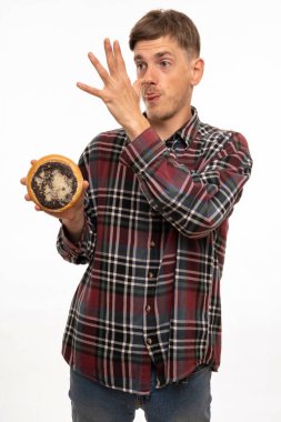 Kahverengi saçlı, uzun boylu, zayıf beyaz bir adam beyaz arka planda izole edilmiş fanila gömlekli bir ahududu tutuyor.