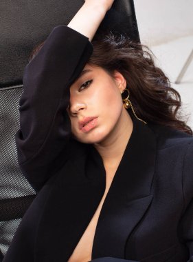 Ofiste siyah deri koltukta beyaz tenli genç Avrupalı bir kızın portresi.