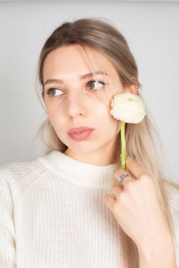 Uzun saçlı ve beyaz tenli romantik bir kadının portresi gri üzerine izole edilmiş elinde küçük bir çiçek tutuyordu.