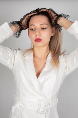 Beyaz elbiseli kadın, uzun saçlı, beyaz tenli, gri portrede soyutlanmış.