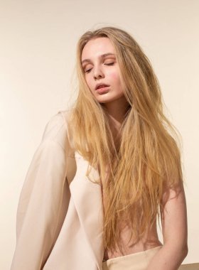 Sarı saçlı, açık renk ceketli, bej renkli genç bir kadın.