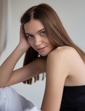 Koyu saçlı, beyaz tenli, koyu gri tenli bir kadın portresi.