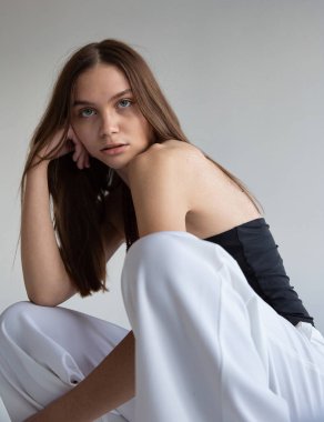 Koyu saçlı, beyaz tenli, koyu gri tenli bir kadın portresi.