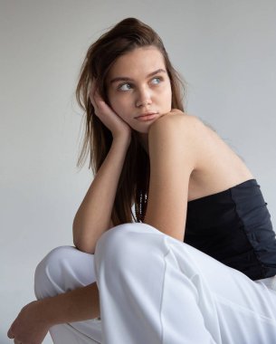 Koyu saçlı, beyaz tenli, koyu gri tenli bir kadın portresi.