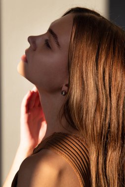 Gün batımında çekilmiş bir portre. Koyu renk saçlı, beyaz tenli, gölgeli bir kadın.