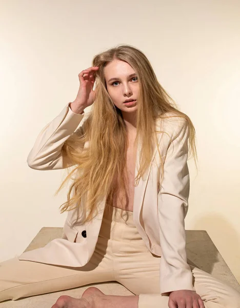Młoda Kobieta Blond Włosami Odizolowana Beżu Siedzi Beżowym Garniturze — Zdjęcie stockowe