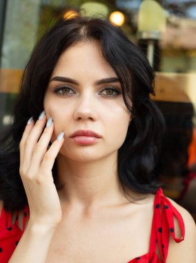 Siyah saçlı, beyaz tenli genç bir kadının portresi. Yüzünün arkasında şehir yansıması var.