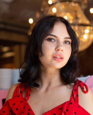 Koyu renk saçlı, beyaz tenli, açık renk dudaklı ve anlamlı gözlü genç bir kadının portresi.