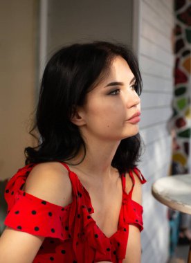 Dolgun dudaklı, beyaz tenli, koyu renk saçlı bir kadının portresi.