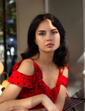 Koyu saçlı, beyaz tenli, kırmızı dudaklı genç bir kadının portresi.