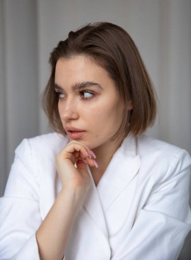Arkaya bakan beyaz Avrupalı kadının portresi. Kısa kesilmiş ve eli yüzünün yanında.