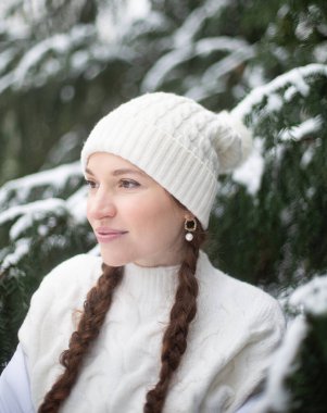 Beyaz tenli ve ladin yakınlarında uzun örgülü saçları olan genç bir kadının portresi.