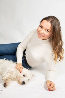 Beyaz kazaklı çekici genç Avrupalı bir kadın. Köpeği beyaz tenli.