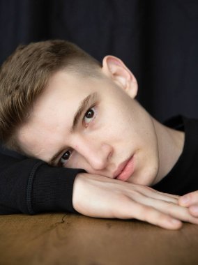 Siyah üzerine izole edilmiş genç sarışın portresi masaya ve eline yaslanmış.