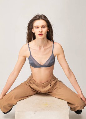 Koyu renk düz saçlı, genç, zayıf bir kadın. Bej renkli, bacakları ayrık.