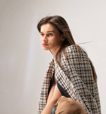 Stüdyoda omuzlarında ekose ceketi olan zayıf bir kadının portresi.