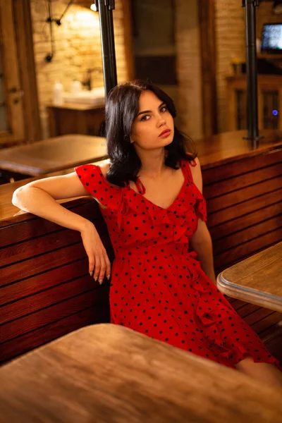 Siedząca Młoda Ciemnowłosa Kobieta Białą Skórą Restauracji Czerwonej Sukience Kropką — Zdjęcie stockowe