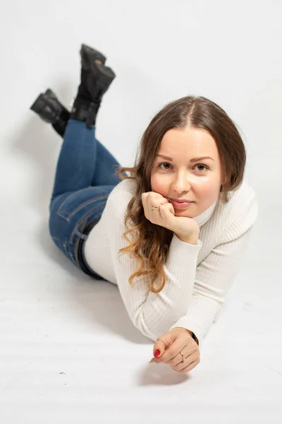 魅力的な若いですヨーロッパの女性で暖かい白いジャンパーは床に横たわっている上に隔離 — ストック写真