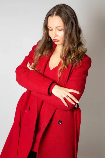 迷人的年轻欧洲女人 身穿红色外套 与浅灰隔离 双臂交叉 — 图库照片