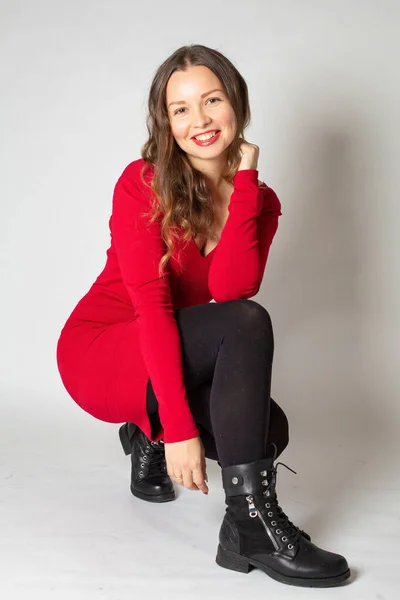 Agachando Atraente Jovem Mulher Europeia Vestido Vermelho Isolado Cinza — Fotografia de Stock