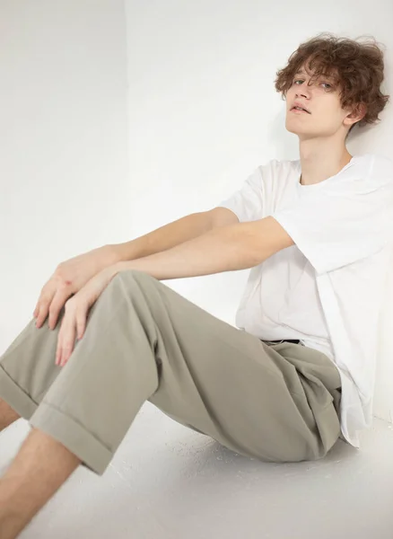 Aantrekkelijke Jonge Europese Man Geïsoleerd Beige Zittend Vloer Wit Shirt — Stockfoto