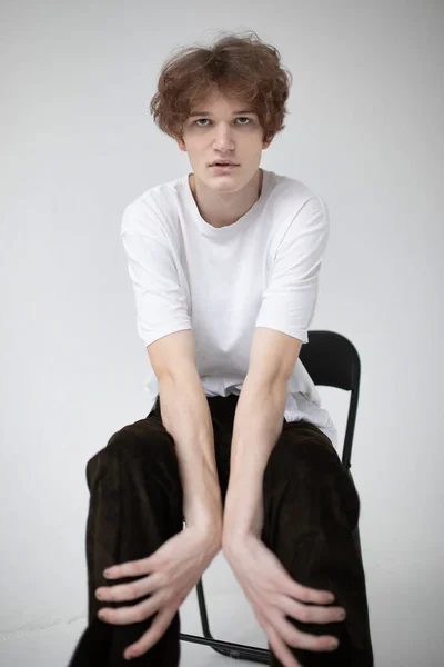 魅力的な若いヨーロッパの男を曲げ前方に座って孤立ライトグレー — ストック写真