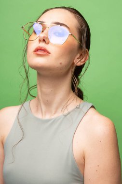 Yeşil gözlüklü koyu renk saçlı genç bir kadının portresi.