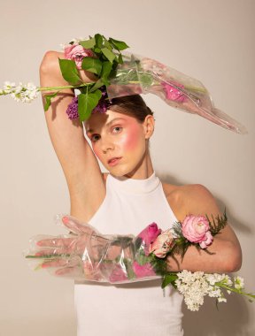 Avrupai saçları ve pastel çiçekleri olan Avrupalı bir kadın açık bej üzerine izole edilmiş ellere yapışmış.