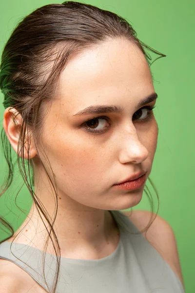 緑に隔離された茶色の目を持つ濃い髪を集めた若い女性のクローズアップ肖像画 — ストック写真