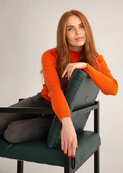 穿着橙色连衣裙的红头发女人 与米色隔离 坐在椅子上 — 图库照片