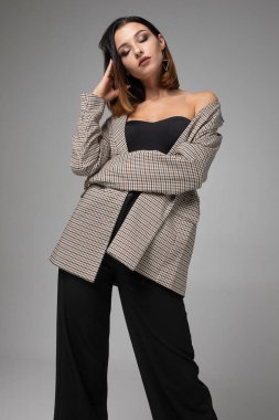 Kısa siyah saçlı, zayıf genç bir kadın koyu gri üzerinde gözleri kapalı duruyor.