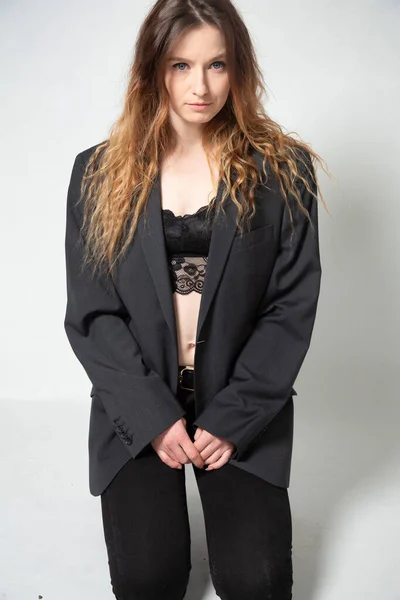 黒のジャケットでグレーに隔離された長い巻き毛を持つ白い若いヨーロッパの女性 — ストック写真