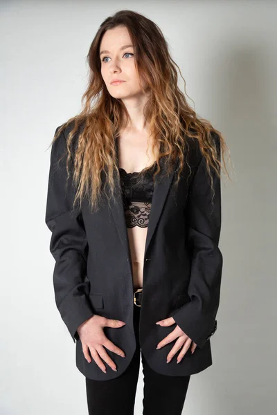 黒のジャケットでグレーに隔離された長い巻き毛を持つ白い若いヨーロッパの女性 — ストック写真