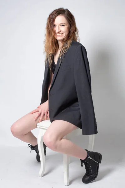 白い若いヨーロッパの女性が椅子に座っているライトグレーで隔離された合計黒 — ストック写真
