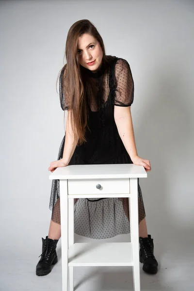 若いですホワイトヨーロッパの女性で黒のドレスグレーの上に隔離された白いナイトスタンド — ストック写真