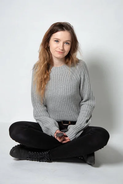 Weiße Junge Europäerin Mit Langen Lockigen Haaren Grauem Strickpullover Sitzt lizenzfreie Stockbilder