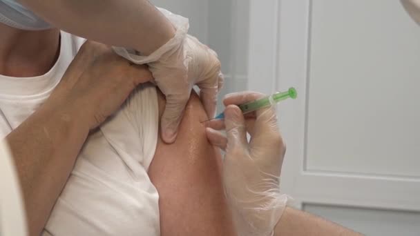Близько до жінки-лікаря, який тримає шприц, роблячи ковадлу 19 ін'єкційну дозу вакцинації в плечі старшого чоловіка. Вакцинація літнього пацієнта, концепція охорони здоров'я. вакцина проти коронавірусу Covid-19 Стокове Відео 