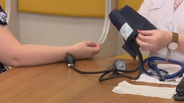 Nurse or female doctor puts on tonometer on arm of woman in the hospital — Stock Video