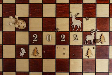 Bir vezir ve diğer taşlarla birlikte yeni yıl kompozisyonu, 2022 ahşap satranç tahtası, kompozisyon renkleri - kahverengi, siyah. Düz konum, kopyalama alanı, üst görünüm. Yüksek kalite fotoğraf
