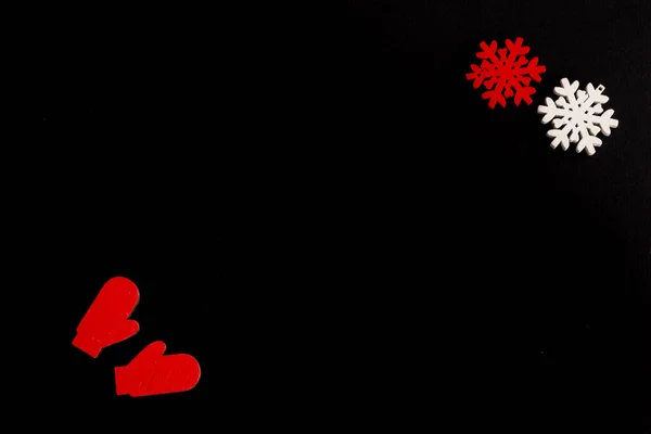 2022, siyah arka planda şık bir Noel kompozisyonu, kar taneleri ve eldivenlerden ahşap heykelcikler, kopyalama alanı. Yüksek kalite fotoğraf